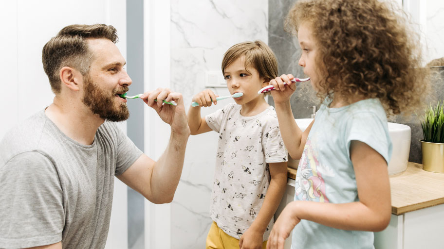 Dad teaching kids how to brush their teeth - Why Dental Hygiene is Important